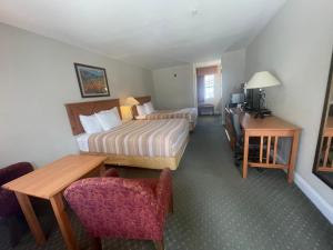 a hotel room with a bedroom with a bed and a desk at Stagecoach Inn Woodville in Woodville