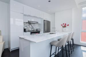 a white kitchen with a counter and stools at Le Se7t Penthouses in Montreal