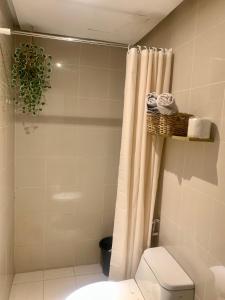 a bathroom with a shower with a toilet and a shower curtain at Scandi Minimalist Mckinley Hill BGC in Manila