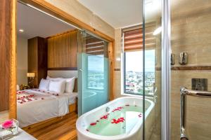 ein Badezimmer mit einer Badewanne und ein Schlafzimmer mit einem Bett in der Unterkunft Nhu Minh Plaza Danang Hotel in Đà Nẵng