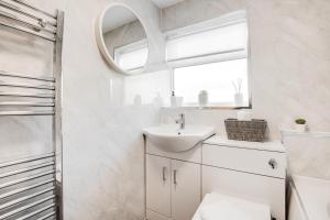 a white bathroom with a sink and a mirror at Silver Stag Properties, 3 BR Gem with 2 Baths in Hugglescote