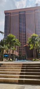 a large building with palm trees in front of it at Bintang Lux B&B Suites Times Square KL in Kuala Lumpur