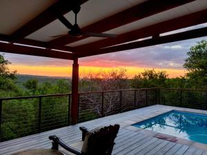 una terraza con piscina, silla y puesta de sol en Ndlovu Bushvilla at Elephant Rock Eco Estate en Mica