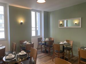 - une salle à manger avec des tables, des chaises et un miroir dans l'établissement Hôtel P.L.M., à Cannes