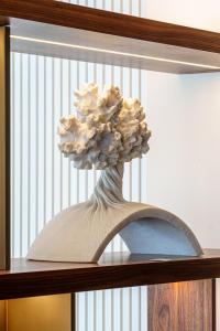 a vase of flowers sitting on top of a shelf at Hotel Dom Goncalo & Spa in Fátima