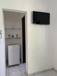 pared blanca con TV de pantalla plana en la pared en Chalés e suítes Lourenço, en Ilhabela