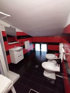 een rood-witte badkamer met 2 toiletten en een wastafel bij HOTEL POSIDONIA INN SAPRI in Sapri