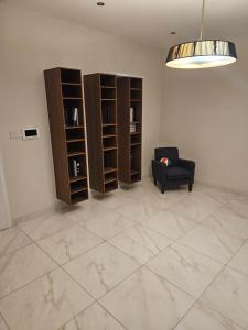 a living room with a chair and book shelves at Double bedroom in shared Penthouse Apartment - Seabreeze Terraces in St Paul's Bay