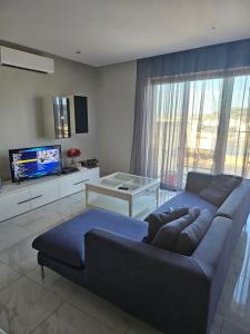 a living room with a blue couch and a tv at Double bedroom in shared Penthouse Apartment - Seabreeze Terraces in St Paul's Bay