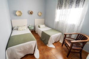 a room with two beds and a chair and a window at Atlantic View La Caleta Adeje in Adeje