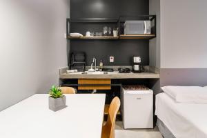 una pequeña cocina con fregadero y mesa en Studio 2 Pinheiros by Oba, en São Paulo