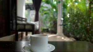 a white coffee cup and saucer on a table at The Otunna Guest House Sigiriya in Sigiriya