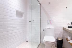 baño blanco con aseo y ducha acristalada en Studio 2 Pinheiros by Oba, en São Paulo