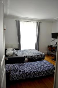 two beds in a room with a window at CdH Lantiez in Paris