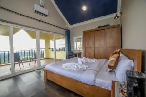 a bedroom with a large bed and a balcony at Eagles Wings Abode in Coonoor