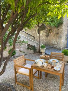 einen Holztisch, 2 Stühle und einen Tisch mit Geschirr in der Unterkunft Le Jardin D'Elma in Vence