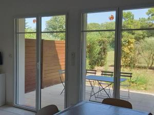 a room with sliding glass doors and a table and chairs at Maison à Notre-Dame-de-Monts avec piscine, wifi et parking, 4 personnes - FR-1-540-145 in Notre-Dame-de-Monts