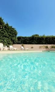 una piscina con agua azul y sillas blancas en Appartement en Montélimar