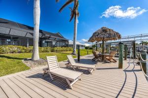 a deck with chairs and tables and a straw umbrella at Villa Thunderbird View, Cape Coral in Cape Coral