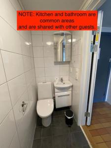 un baño con aseo y un letrero en la pared en Lillehammer Guest House with common bath and kitchen en Lillehammer