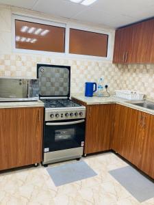 a kitchen with a stove and wooden cabinets at Yoi Pod Hostel - Deira Al Rigga in Dubai