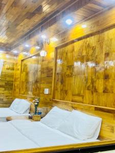two beds in a room with a wooden wall at Sun Hill's House in Cham Ta Lao