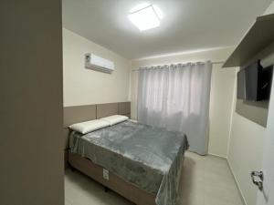Dormitorio pequeño con cama y TV en Apartamento Novo Praia de Bombas en Bombinhas