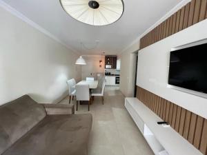 Apartamento Novo Praia de Bombas في بومبينهاس: غرفة معيشة مع أريكة وتلفزيون على جدار