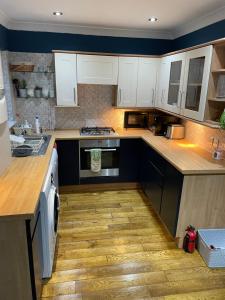 a kitchen with white cabinets and a stove top oven at Lovely 4 bed house with patio & bbq in Slades Green
