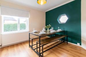 諾丁漢的住宿－Your Nottingham Haven - 3 Bed House with Free Wifi and Parking，一间设有桌子和绿色墙壁的用餐室