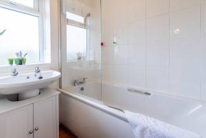 La salle de bains blanche est pourvue d'un lavabo, d'une baignoire et d'un lavabo. dans l'établissement Your Nottingham Haven - 3 Bed House with Free Wifi and Parking, à Nottingham