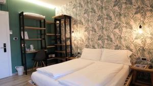 a bedroom with a white bed with a wall at Hotel Villa Alberta in Nago-Torbole