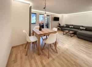 - un salon avec une table en bois et des chaises blanches dans l'établissement Chalet Ribi, à Grindelwald