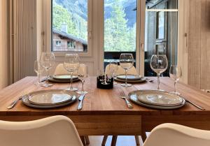 uma mesa de madeira com copos de vinho e pratos em Chalet Ribi em Grindelwald