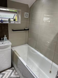 a bathroom with a tub and a sink at Lovely 4 bed house with patio & bbq in Slades Green +20 photos