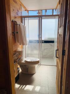 een badkamer met een toilet en een glazen schuifdeur bij Parque Cueva de los Leones - Rimusa Inn in Creel