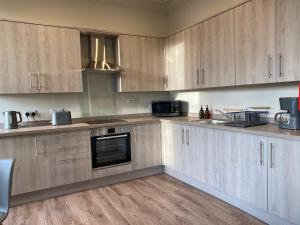 a large kitchen with wooden cabinets and appliances at Ballater, Entire home hosted by Catherine in Ballater