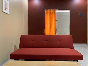 a red couch in a room with an orange curtain at Simple Home near Baturraden in Rempawah