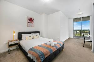 a bedroom with a bed and a desk and a window at Spacious 2 beds Apt near Airport in Sydney