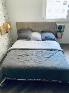 ein großes Bett mit blauer Bettwäsche und Kissen in einem Schlafzimmer in der Unterkunft Très bel appartement Dunkerque centre, en Citadelle in Dunkerque
