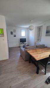 a living room with a wooden table and a couch at Logement avec grand balcon dans le Brionnais in Chauffailles +17 photos