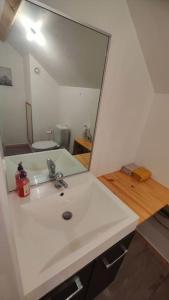a bathroom with a white sink and a large mirror at Logement avec grand balcon dans le Brionnais in Chauffailles