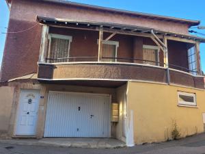 a building with a balcony and a garage at Logement avec grand balcon dans le Brionnais in Chauffailles