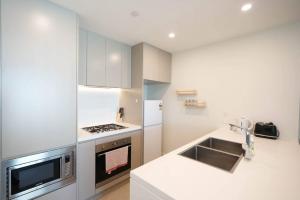 cocina blanca con fregadero y microondas en Superior View APT in heart of Sydney Olympic Park, en Sídney