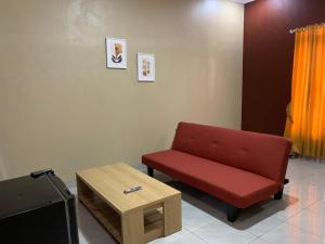 a waiting room with a red couch and a coffee table at Simple Home near Baturraden in Rempawah