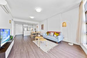 ein Wohnzimmer mit einem Sofa und einem Tisch in der Unterkunft Lovely 2 bedroom APT in centre of Sydney Olympic Park in Sydney