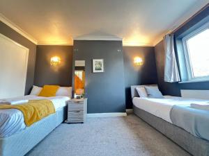 a bedroom with two beds and a window at Airport Garden Rooms in Feltham