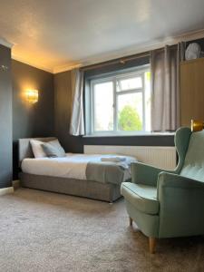 - une chambre avec un lit, une chaise et une fenêtre dans l'établissement Airport Garden Rooms, à Feltham