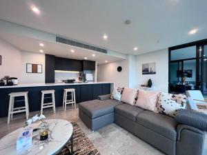 ein Wohnzimmer mit einem Sofa und einer Küche in der Unterkunft High Level Fabulous View 4Beds APT in Olympic Park in Sydney
