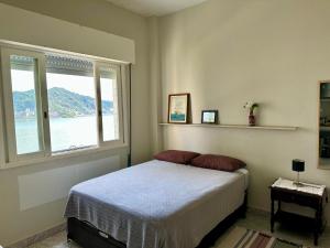 um quarto com uma cama e uma grande janela em Kitnet pé na areia! Vista espetacular ! em São Vicente